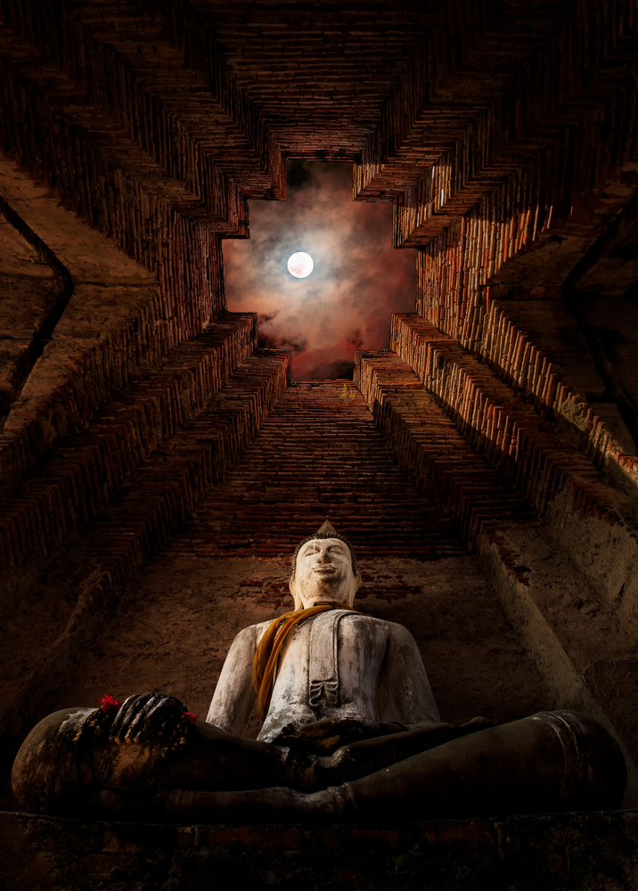 Ancient buddha statue under full moon - Old temple at Prasat Nakhon Luang, Ayutthaya, Thailand. Photo - Stock Image